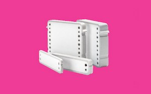 Technician in a white coverall adjusts a single-use bioprocess tubing assembly with hanging fluid bags, filters, and clamps on a metal frame, flanked by benchtop pump/control equipment, against a blue background.