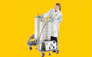 Viresolve Pro Technician in a white coverall adjusts a single-use bioprocess tubing assembly with hanging fluid bags, filters, and clamps on a metal frame, flanked by benchtop pump/control equipment, against a blue background.