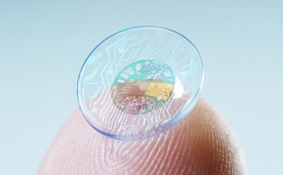 Contact lens with sensor in middle held on fingertip. Contact lens with sensor in middle held on fingertip.