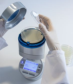 Viable Air Sampling with the MAS-100 NT® active air sampler Scientist performing viable air sampling with the MAS-100 NT<sup>®</sup> air sampler and a settle plate