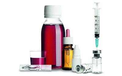 Liquid Formulation From left to right, the image shows a cup with a red liquid, a glass container of the same red liquid, a brown glass vial with a dropper for a lid, a plastic bottle of eye drops, a glass vial lying on its side, and a glass vial containing a clear liquid with a syringe inserted at the top.