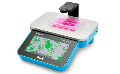 Photograph of the Millicell® DCI Digital cell imager for measuring confluency and cell count, with plate of hanging cell culture inserts in 24-well format on platform Photograph of the Millicell® DCI Digital cell imager for measuring confluency and cell count, with plate of hanging cell culture inserts in 24-well format on platform
