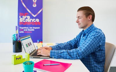 Photograph of scientist sitting at a desk in an office using Millicell® Cloud features to analyze data Photograph of scientist sitting at a desk in an office using Millicell® Cloud features to analyze data