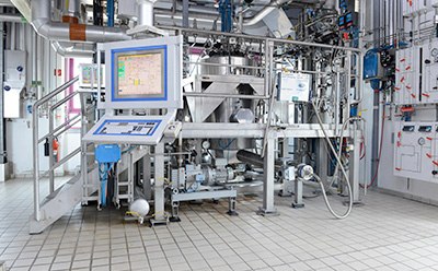 Pilot plant - catalysis and pressure reactions for new products Work floor of a small pilot plant showing a control panel with stainless steel tanks and piping