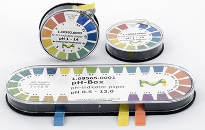 Three containers of pH indicator paper strips, each with a color-coded pH range chart on the lids. The containers are cylindrical, with one lying horizontally and two stacked vertically, all shown against a white background. Each container also has a small piece of tape in various colors to presumably mark different pH ranges. Three containers of pH indicator paper strips, each with a color-coded pH range chart on the lids. The containers are cylindrical, with one lying horizontally and two stacked vertically, all shown against a white background. Each container also has a small piece of tape in various colors to presumably mark different pH ranges.