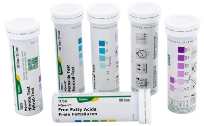 MQuant® Test Strips for Semiquantitative Testing  Five cylindrical containers with diagnostic test strips, each marked with different labels indicating specific tests, such as free fatty acids and other chemical indicators. The containers are variously labeled with color codes and measurement scales, suggesting they are used for specific biochemical tests.