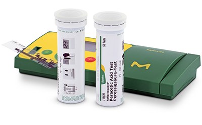 Reflectoquant® Test Strips and Reader for Quantitative Testing Two cylindrical containers of diagnostic test strips positioned next to a green box labeled with a yellow and green design and medical symbols. The containers have labels providing information about the test strips inside, and one container is open with a strip partially extended, suggesting readiness for use in a clinical or laboratory setting.
