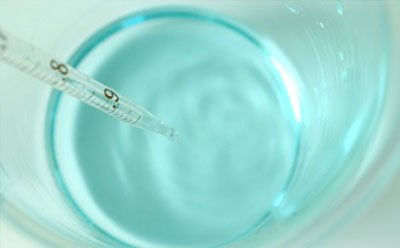 Biological buffer solution in beaker Light blue biological buffer solution in beaker with pipette.