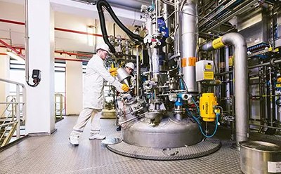 Chemical Catalysts for pharma and industrial applications Two technicians working on large, two-story vessel for catalyst production