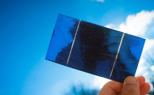Solar Energy Materials  A thin, blue solar cell is held up by hand to sunlight.