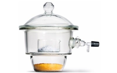 A round glass container with a tightly sealed lid that features a knob on top for easy handling. Inside the desiccator, there are two chambers: the upper chamber holds a small, transparent dish containing a white or grayish substance, likely a sample. The lower chamber contains an orange, granular material, a desiccant, which absorbs moisture. The desiccator is equipped with a side valve for vacuum connection, allowing for the removal of air to create a low-moisture environment. The entire apparatus is made of clear glass, giving it a sleek appearance.  A round glass container with a tightly sealed lid that features a knob on top for easy handling. Inside the desiccator, there are two chambers: the upper chamber holds a small, transparent dish containing a white or grayish substance, likely a sample. The lower chamber contains an orange, granular material, a desiccant, which absorbs moisture. The desiccator is equipped with a side valve for vacuum connection, allowing for the removal of air to create a low-moisture environment. The entire apparatus is made of clear glass, giving it a sleek appearance.