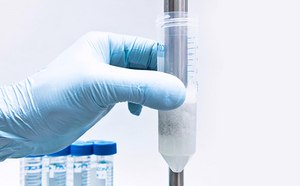 Grinders & Homogenizers A close-up image of a gloved hand holding a clear centrifuge tube containing a white precipitate at the bottom. The tube is marked with measurement lines, and there are additional tubes in the background, all against a clean, light blue backdrop. This image is relevant as it depicts a common laboratory procedure for separating substances based on density, which is essential in many scientific research and diagnostic processes.