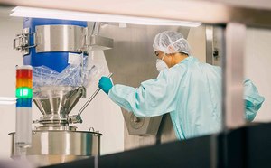 Downstream Process & Formulation Chemicals  Technician overseeing bioreactor for chemical processing, featuring a professional in protective clothing meticulously monitoring a stainless steel bioreactor, which is integral to downstream processing and formulation in the chemical industry, within a cleanroom environment.