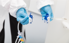 NovaSeptum® SURe sterile sampling assembly with AseptiQuik® S connector Hands in blue gloves working with small electrical connectors. The person is wearing a white lab coat, suggesting a professional or laboratory setting. There are colored wires attached to the connectors.