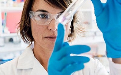 Professional Laboratory Scientist Conducting Experiment The image depicts an individual in a white lab coat and blue gloves, indicating a scientific or medical setting.