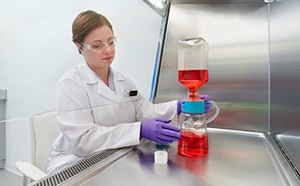 Millipore® Sterile Filters The image show a woman in a white lab coat, working with laboratory flask containing a red liquid, which is connected to another piece of equipment with blue liquid at the bottom.