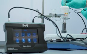 <p>Selective Synthesis Using Light and Electricity</p>
 A close-up of a laboratory setup featuring a digital device with a touchscreen interface labeled "Sigma 400," connected to a scientific apparatus. A gloved hand is manipulating the equipment in the background.
