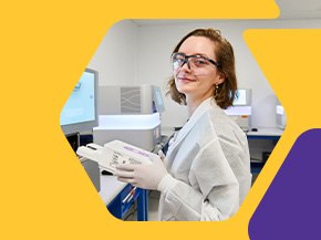 Scientist in a lab coat and gloves operates a benchtop instrument and computer monitor in a clean laboratory, framed by a yellow hexagonal graphic with a purple corner accent.