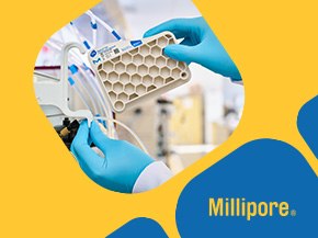a laboratory setting where a hand, wearing a blue glove, is handling a Natrix® CH membrane chromatography device. The device features a honeycomb-like structure and is connected to various tubes, indicating its use in a chromatography process. The background is softly blurred, focusing attention on the equipment.