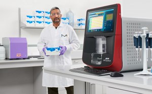 Preclinical Development Smiling scientist sitting in front of bench with a microscope, CellASIC® ONIX2 live cell imaging system, and computer monitor