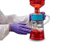 Sterile Media Filtration A scientist wearing purple gloves holds a red filter.