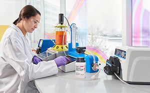 USP Cell Retention A scientist works on a bioreactor while sitting at a white counter next to a window.