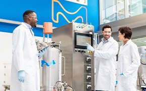 Upstream Processing (USP) for mAbs 3 operators discussing in front of a single-use bioreactor with a technician pointing at the system’s HMI screen.