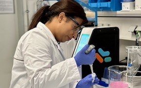 Mehta lab tile Aditi wears PPE and uses a pipette to extract a solution in the lab.