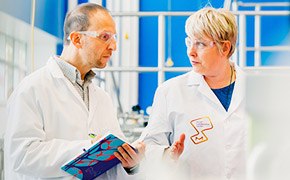 Scientists in the M Lab™ One scientist explaining new innovation to another scientist in front of a blue window