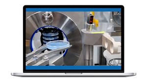 A close-up view of a mechanical assembly in a manufacturing setting, featuring robotic arms handling a round blue component. The background includes a shiny metallic surface and a circular opening, suggesting a high-tech environment. The scene is displayed on a laptop screen.