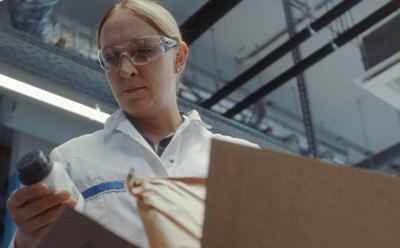 Person in a lab coat examining bottle and packaging materials Person in a lab coat examining bottle and packaging materials