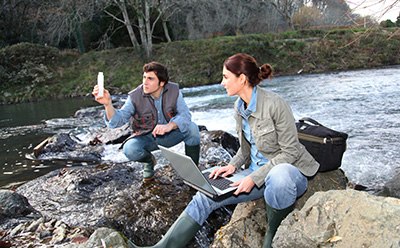 Photomertry at a River Two scientists testing the water at a river.