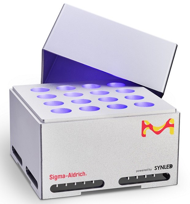 SynLED Parallel Photoreactor SynLED Parallel Photoreactor 2.0 against a white background. The device is a light grey cuboidal box with its cover partially open, revealing 16 vials illuminated by a 1 W blue LED centered at 467.5 nm, equipped with a 45° lens. The side facing the viewer displays a vibrant M logo in yellow and red at the top right corner.