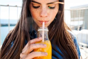 Juice testing for food safety Woman drinking orange juice with a straw