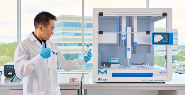 Scientist standing in front of AAW™ automated assay workstation with PureProteome™ stand giving a thumbs up.