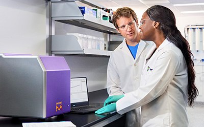 Expertise in SMC® Technology Image of 2 scientists having a conversation in front of the SMCxPRO® immunoassay platform that uses SMC® technology.