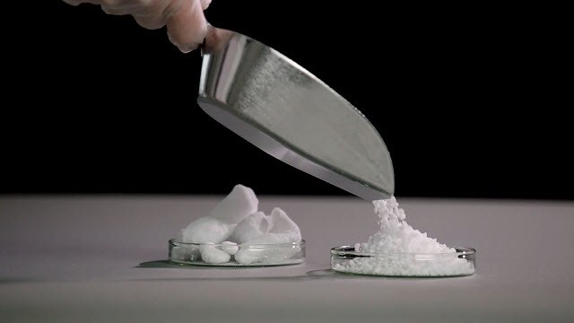 <p>Granulated Raw Materials for Pharmaceutical Processes</p>
 White granulated material is being poured into a petri dish on a gray counter.
